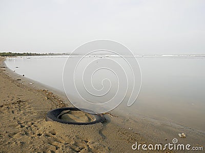 Buried tire on the shore of a caribbean beach near cartagena colombia with birds on the background pollution Stock Photo