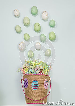 Easter basket spills eggs on green pastel background Stock Photo
