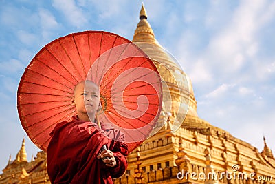 Burmese Buddhist monk walk with umbella in Shwezigon Paya golden pagoda Stock Photo