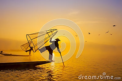 Burmese fisherman on bamboo boat catching fish in traditional way with handmade net. Inle lake, Myanmar Burma travel destination Stock Photo