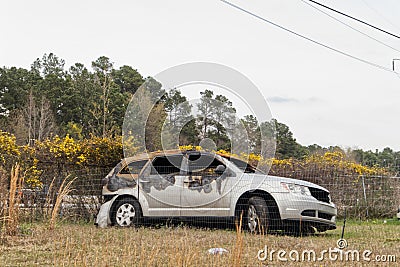 A burned minivan from a fire behind a wire fence Editorial Stock Photo