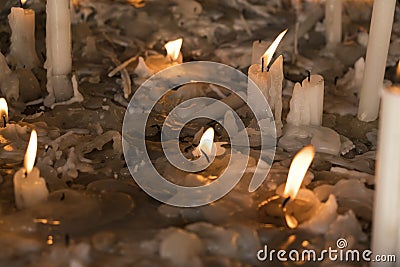 White burning and burnt down candles surrounded by melt wax Stock Photo