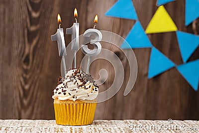 Burning candle - birthday number 113 on wooden background with pennants Stock Photo