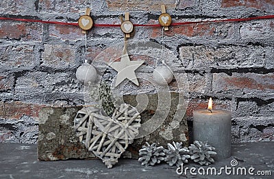 Burning candle and Christmas decoration in front of brick wall Stock Photo