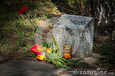 Burning candle and flowers tulips vested at the monument Editorial Stock Photo