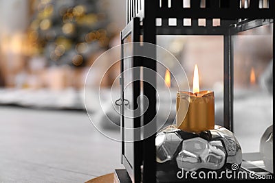 Burning candle in lantern against blurred background. Stylish interior element Stock Photo