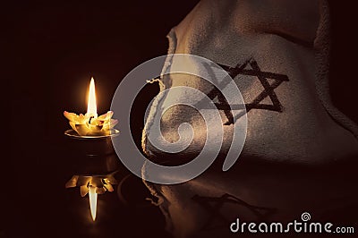 A burning candle next to the star of David Editorial Stock Photo