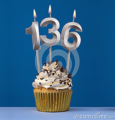 Burning candle number 136 - Birthday card with cupcake on blue Background Stock Photo
