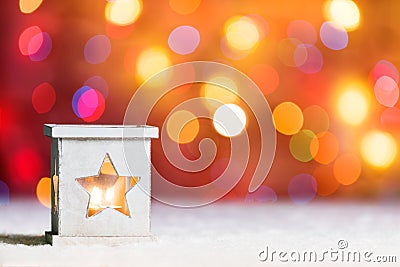 Burning candle, in snow, with defocussed fairy lights, boke in the background, Festive Christmas background Stock Photo