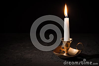 Burning candle in vintage candlestick on black background Stock Photo