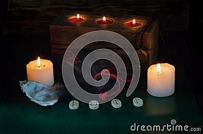 Burning candles, a bag with runes and a formula of the symbols Fehu, Mannaz, Tiwaz and Wunjo Stock Photo