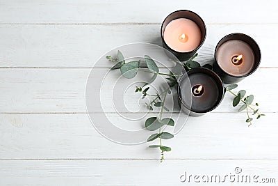 Burning candles and green branches on white wooden table, flat lay. Stock Photo