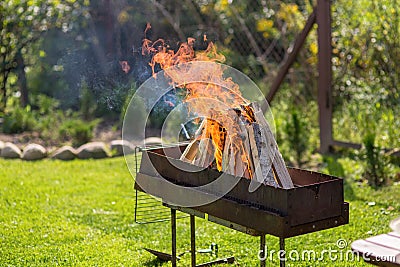 Burning firewood in a barbecue in nature. Beautiful hot flames and smoke. Stock Photo