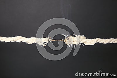 Burning frayed rope at breaking point Stock Photo