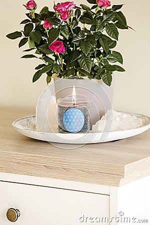 Burning glass candle with homemade sign showing Flower of Life symbol in home interior with semi precious stone geodes. Stock Photo