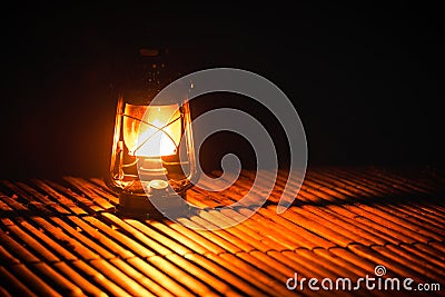 Burning kerosene old lamp on bamboo wooden, lighting in camping at night Stock Photo