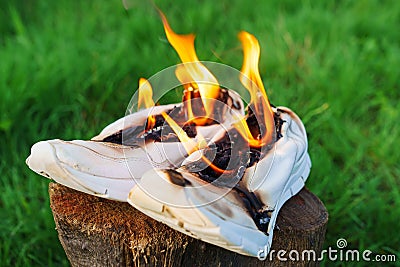 Burning leather sports shoes. Sneakers or gym shoes on fire stand on the Stump. Stock Photo