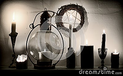 Burning magic candles on the shelf and pentagram on the wall Stock Photo