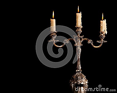 Burning old candle vintage Silver bronze candlestick. Isolated Black Background. Stock Photo