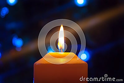 A burning orange candle on a dark background with blue lights - a Christmas New Year`s eve divination mystic esoteric romance lov Stock Photo