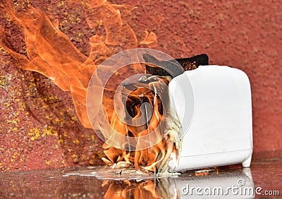 Burning toaster. Toaster with toast caught on fire over table Stock Photo