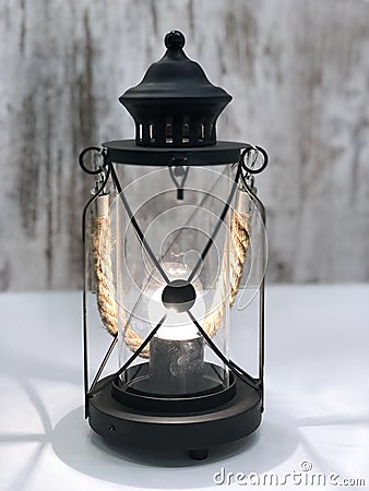 Burning vintage black lamp decorated with a rope. Stock Photo