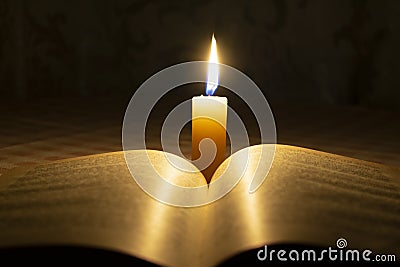 A burning wax candle illuminates Stock Photo