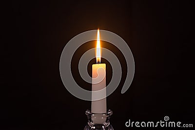 Burning white candle on a black background Stock Photo