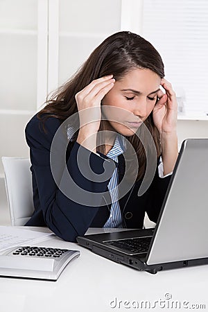 Burnout: overworked tired businesswoman in blue scratching head Stock Photo