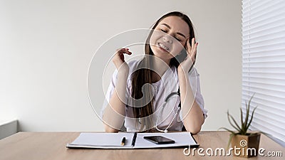 Burnout at work, young caucasian woman doctor sitting at a table in a hospital. Headache, failure, frustration, migraine Stock Photo