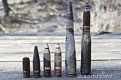 Burnt large-caliber shells and bullets with and without sleeves, affected by the explosion near on a wooden table Stock Photo