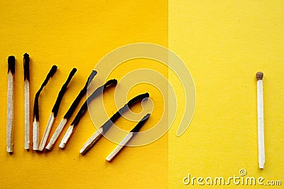 Burnt matches and a whole match on a yellow background. Stock Photo