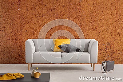 Burnt orange wabi sabi living room interior with grey couch with yellow and black pillows and newspaper rack Stock Photo