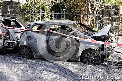 burnt out car wrecks behind police tape in residential street in Germany Stock Photo