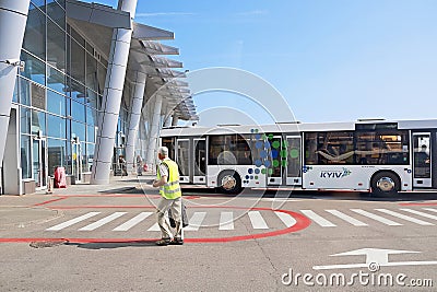Bus, airport building and unidentified airport worker. Igor Sikorsky Kyiv International Airport Zhuliany Editorial Stock Photo