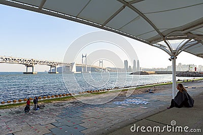 People relaxing and enjoying view of Busan Gwangandaegyo Bridge or Diamond Bridge at Millak Waterside Park in Busan, South Korea Editorial Stock Photo