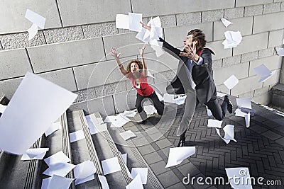 Busines man and woman catching falling paperwork on steps Stock Photo