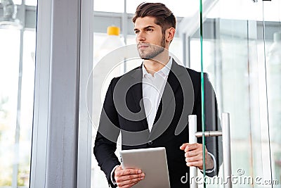 Businesman holding tablet and entering the door in office Stock Photo