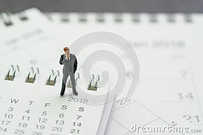 Business appointment, office meeting calendar, miniature businessman thinking and standing on pile of desktop calendars Stock Photo