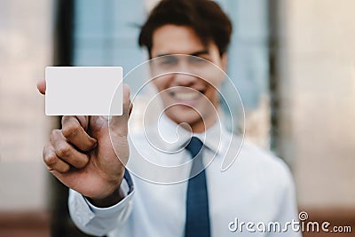 Business Card Mockup Image. Happy Young Businessman Presenting a White Blank Paper Card Stock Photo