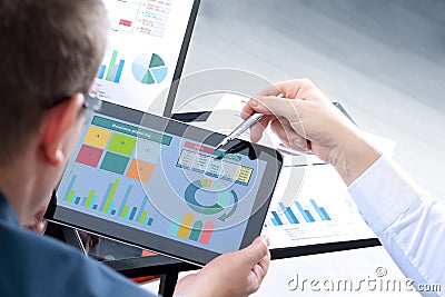 Business colleagues working and analyzing financial figures on a digital tablet. Stock Photo