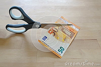 Business concept, fifty Euro banknote is cut with scissors, symbol for wage reduction or pay less money, wooden table, copy space Stock Photo