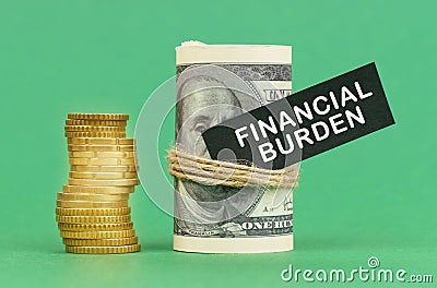 On a green surface are coins and dollars in a bundle. On the dollar sign with the inscription - Financial burden Stock Photo