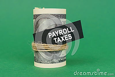 On a green surface, rolled dollars with a black sign that says - payroll taxes Stock Photo