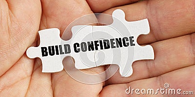 In the hand of a man are puzzles with the inscription - Build Confidence Stock Photo