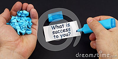 In the hands of crumpled paper, a marker, next to a business card with the inscription - What is success to you Stock Photo