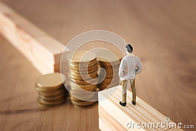 Business concept image of challenge. A man stands on the edge of a gap and looks at a stack of coins, thinking how to earn more Stock Photo