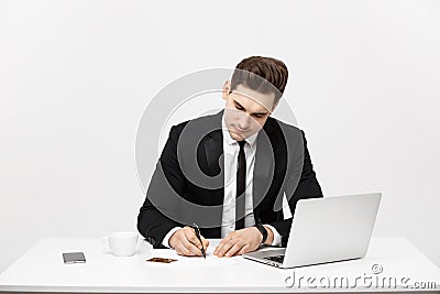 Business Concept: Portrait concentrated young successful businessman writing documents at bright office desk. Stock Photo