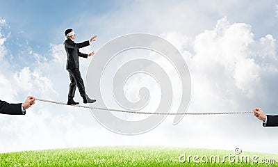 Business concept of risk support and assistance with man balancing on rope Stock Photo