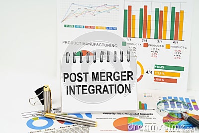 On the table are reports with graphs and a notepad with the inscription - POST MERGER INTEGRATION Stock Photo